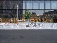 a row of bikes parked next to a tall building next to some steps and trees