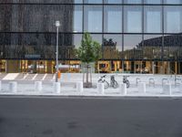 a row of bikes parked next to a tall building next to some steps and trees