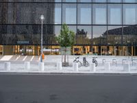 a row of bikes parked next to a tall building next to some steps and trees