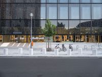 a row of bikes parked next to a tall building next to some steps and trees