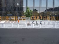 a row of bikes parked next to a tall building next to some steps and trees