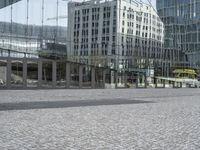 there are some busses and a building reflected in the mirror panels of the building