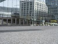 there are some busses and a building reflected in the mirror panels of the building