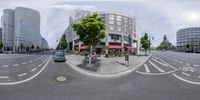 a busy street in the city with cars, bikes and buildings around it and the intersection is shown from a fish eye view