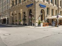 a stop sign in front of an old fashioned building near a street corner with tables and umbrellas