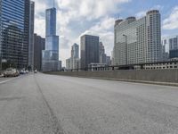 an empty highway on a street with several tall buildings in the background and a yellow van driving along it