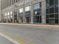 yellow line in the road next to a tall building with large windows and a street light near