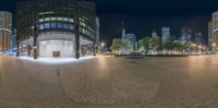 a round sidewalk in a city with multiple stories in it at night time, with an empty street and buildings in the background