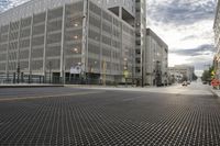 the street is empty with two yellow traffic lights on either side of the road and buildings in the background