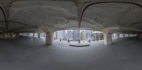 an empty parking garage with many arches, concrete walls and a clock displayed on the wall