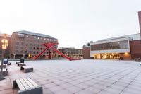 a sculpture on the ground in front of an illuminated plaza and trees with a building behind it