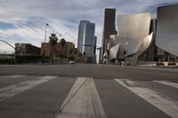 an empty city street in front of some very large buildings as the sun begins to set