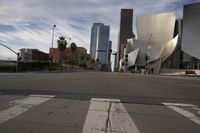 an empty city street in front of some very large buildings as the sun begins to set