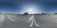 an empty parking lot with sun going down and buildings in the distance at the back