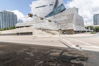 traffic lights are on and near the city center of a futuristic building with large blocks in background