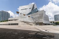 traffic lights are on and near the city center of a futuristic building with large blocks in background