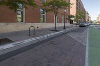 a brick walkway is near the street and sidewalk, near an old building that has windows