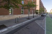 a brick walkway is near the street and sidewalk, near an old building that has windows