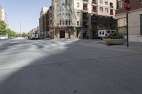 a street view of a wide city street with buildings and cars behind it and a stop sign