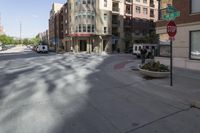 a street view of a wide city street with buildings and cars behind it and a stop sign