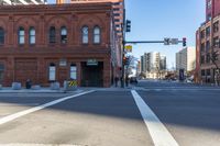 pedestrians crossing an empty street with buildings on both sides of it and one light above them