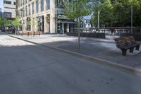 a park bench sitting on the side of the road on a sidewalk with buildings in the background