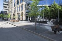 a park bench sitting on the side of the road on a sidewalk with buildings in the background