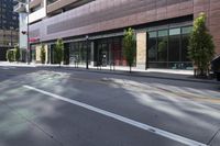 an empty street in the city with buildings on either side of it and cars parked in front