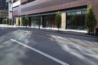 an empty street in the city with buildings on either side of it and cars parked in front