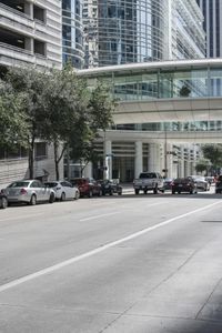 a road with cars parked on both sides of it next to tall buildings in the middle