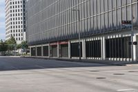 an empty road, with a car parked on it and a tall building with windows