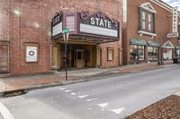 the outside of a theater building with a street corner by it with a red brick building next to it