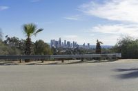 the view of downtown los from an overlook with a bench on it, overlooking the valley and city