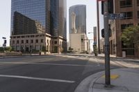 an empty city street with tall buildings and street signs in the background under a hazy sky