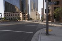 an empty city street with tall buildings and street signs in the background under a hazy sky