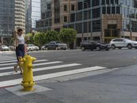 a girl standing on top of a fire hydrant in the street next to the road