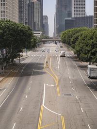 an overhead view of a busy street with several vehicles going down it and tall buildings on either side