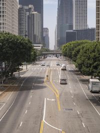 an overhead view of a busy street with several vehicles going down it and tall buildings on either side