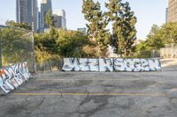 a view of city buildings in the background and some graffiti covered parking lot area with white walls and yellow lines on asphalt