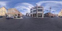 the 360 - view photo depicts a street corner with several buildings, cars and a van parked in front of one