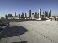 this is an empty building roof in front of a city skylinescape that is in the distance