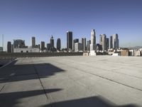 this is an empty building roof in front of a city skylinescape that is in the distance