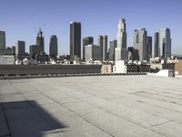 this is an empty building roof in front of a city skylinescape that is in the distance