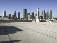 this is an empty building roof in front of a city skylinescape that is in the distance