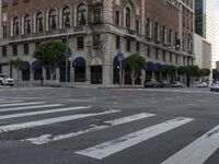 an empty street has an ornate building on one side, and a red brick building on the other