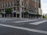 an empty street has an ornate building on one side, and a red brick building on the other