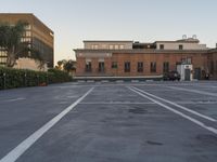 a car is parked in the parking lot and has two buildings at each corner behind it