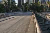 a car is parked underneath the bridge on a city street with tall buildings behind it