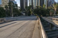 a car is parked underneath the bridge on a city street with tall buildings behind it