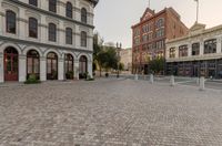 a brick street lined with tall, old fashioned buildings and businesses in the city center